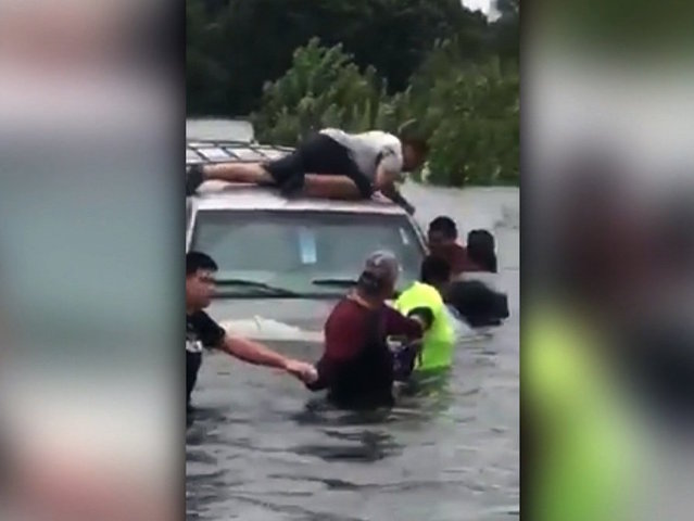 Drivers form a human chain to save a man as floodwaters sweep away his SUV
